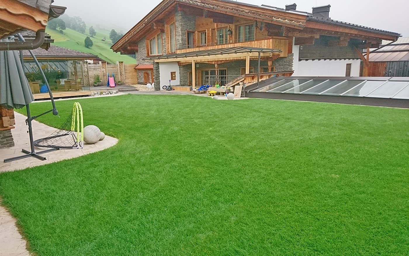 Ein modernes Haus mit Holz- und Steinelementen, umgeben von gepflegtem Rasen